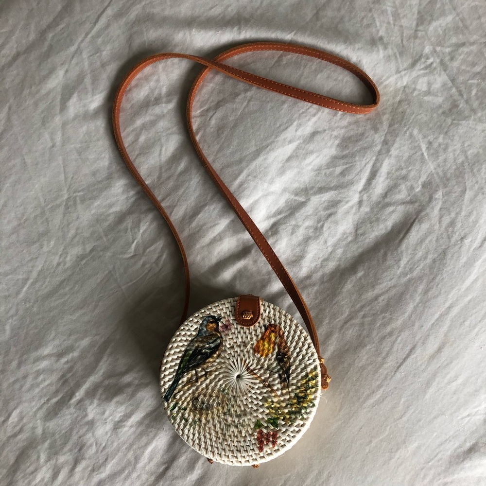Woven white rattan bag with bird appliqué.